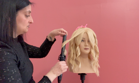 Hairstylist mentre utilizza il ferro arricciacapelli per creare onde e boccoli perfetti.