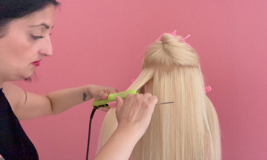 Hairstylist mentre utilizza la piastra per ottenere un liscio perfetto senza rovinare i capelli.