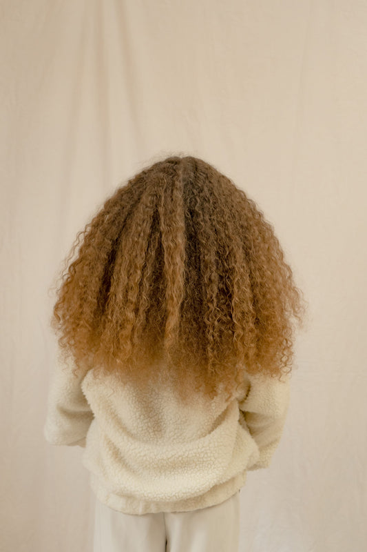 Hairstylist realizza un liscio perfetto su capelli ricci utilizzando una piastra professionale per eliminare il crespo e ottenere una piega liscia, luminosa e disciplinata.